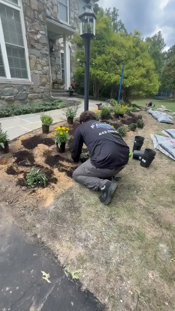 One of our crew, in a Fannon shirt, kneeling to plant a front bed