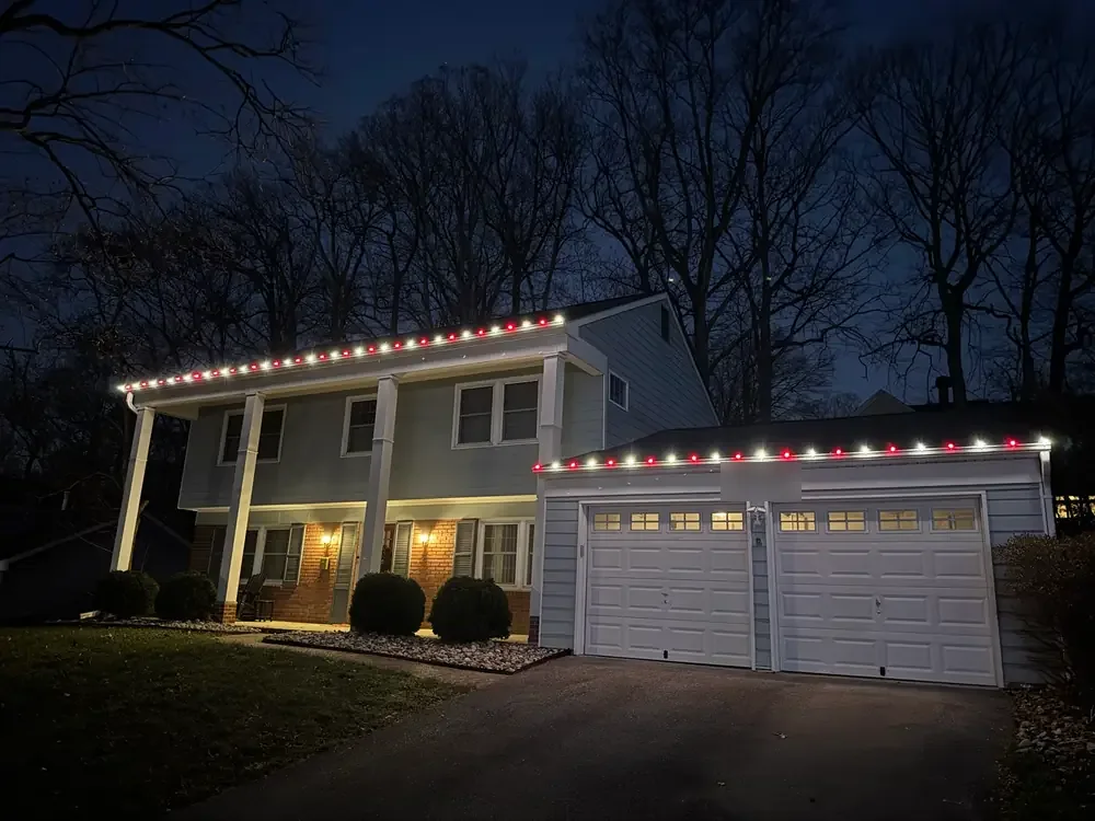 Lights across the front of a two-story home and its garage
