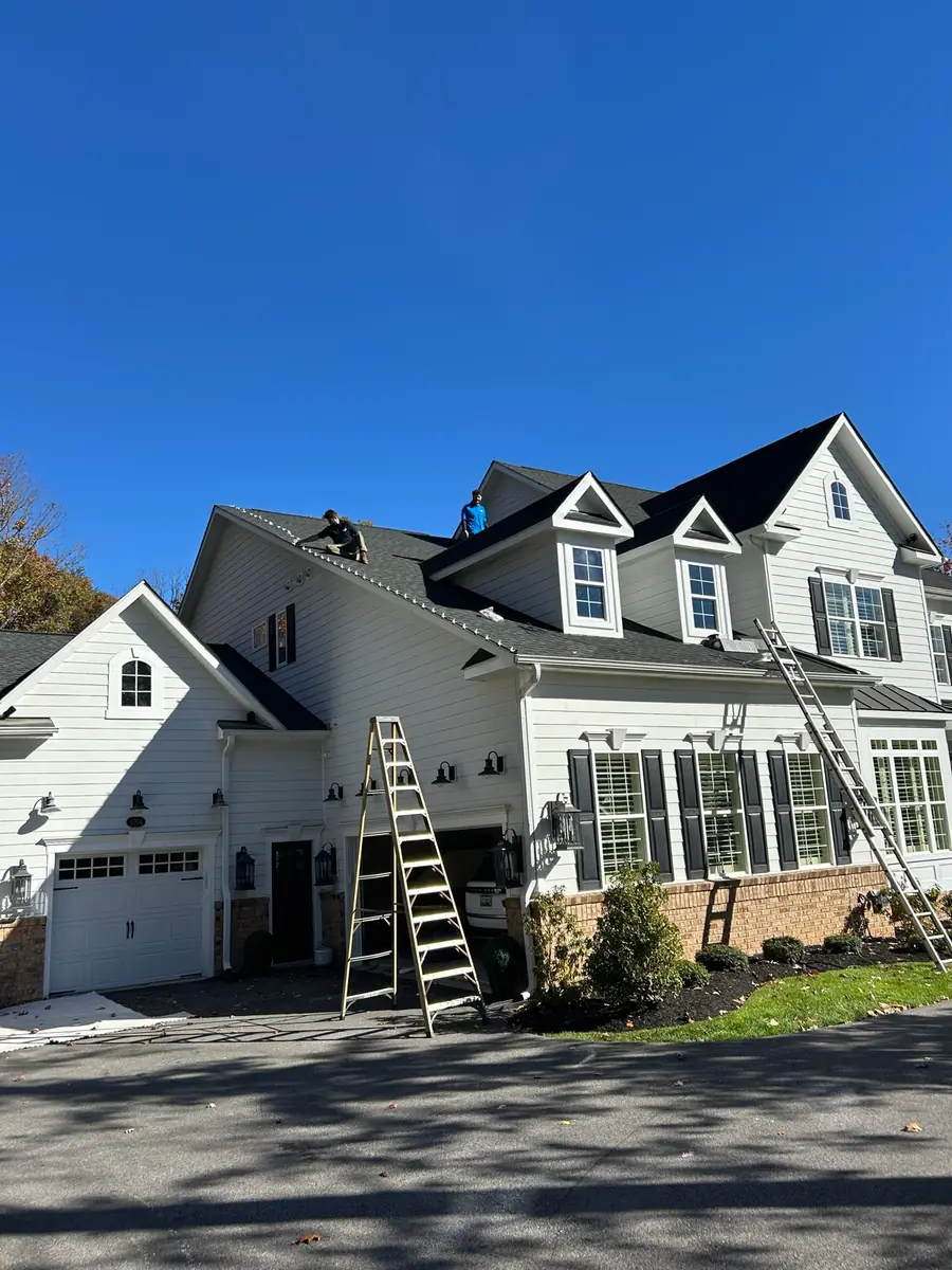 Ladders set up at the front of a white two-story home
